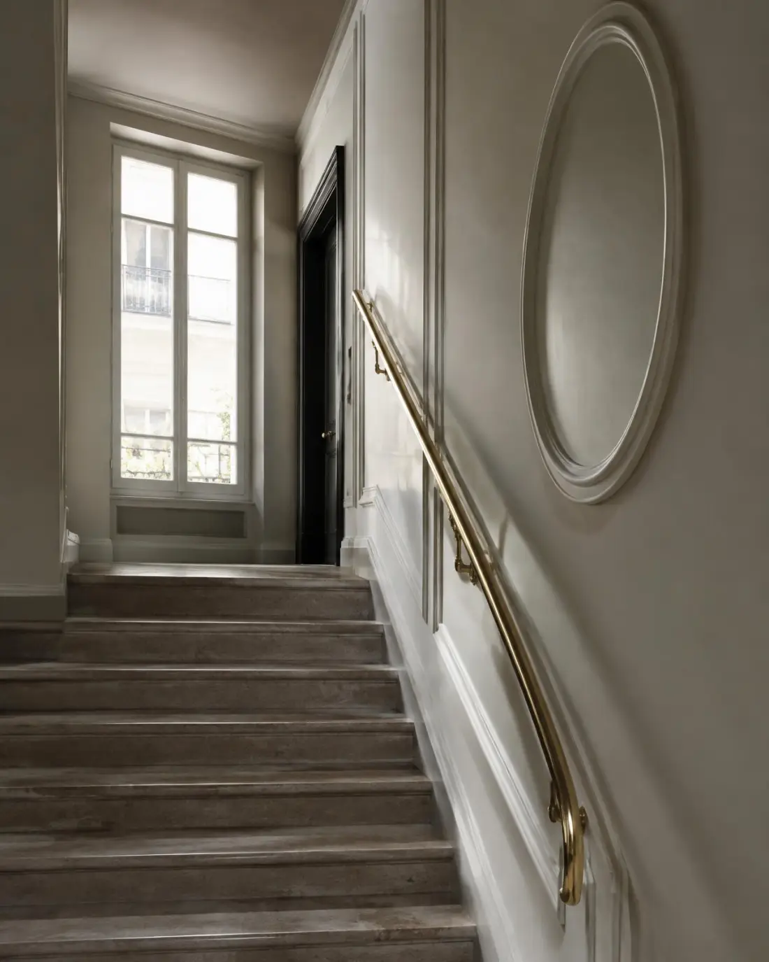 Stairwell of a renovated residential building with stone steps and a brass handrail